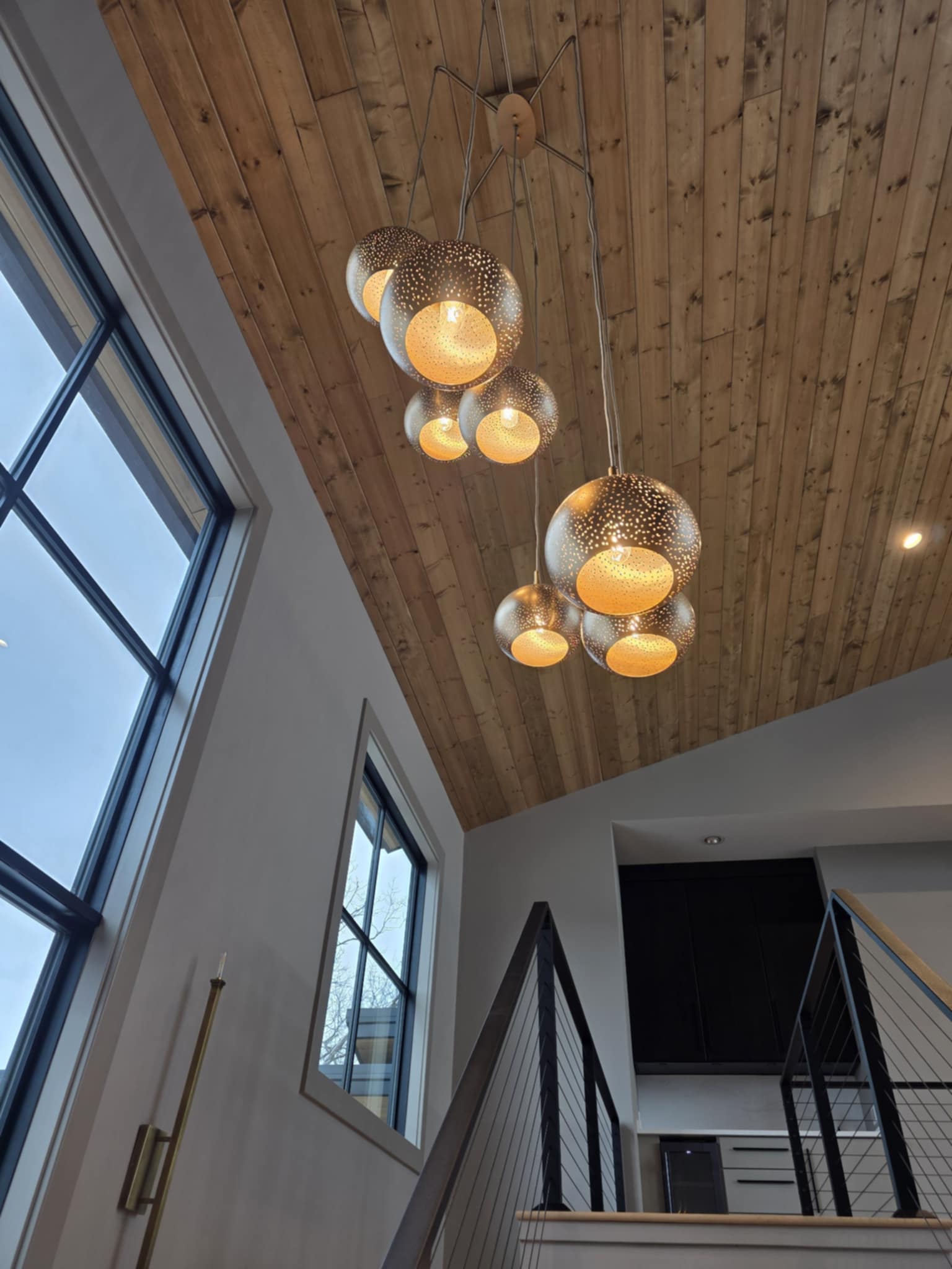 Custom cluster pendant chandelier on wood-plank cathedral ceiling, Cloke Custom Homes