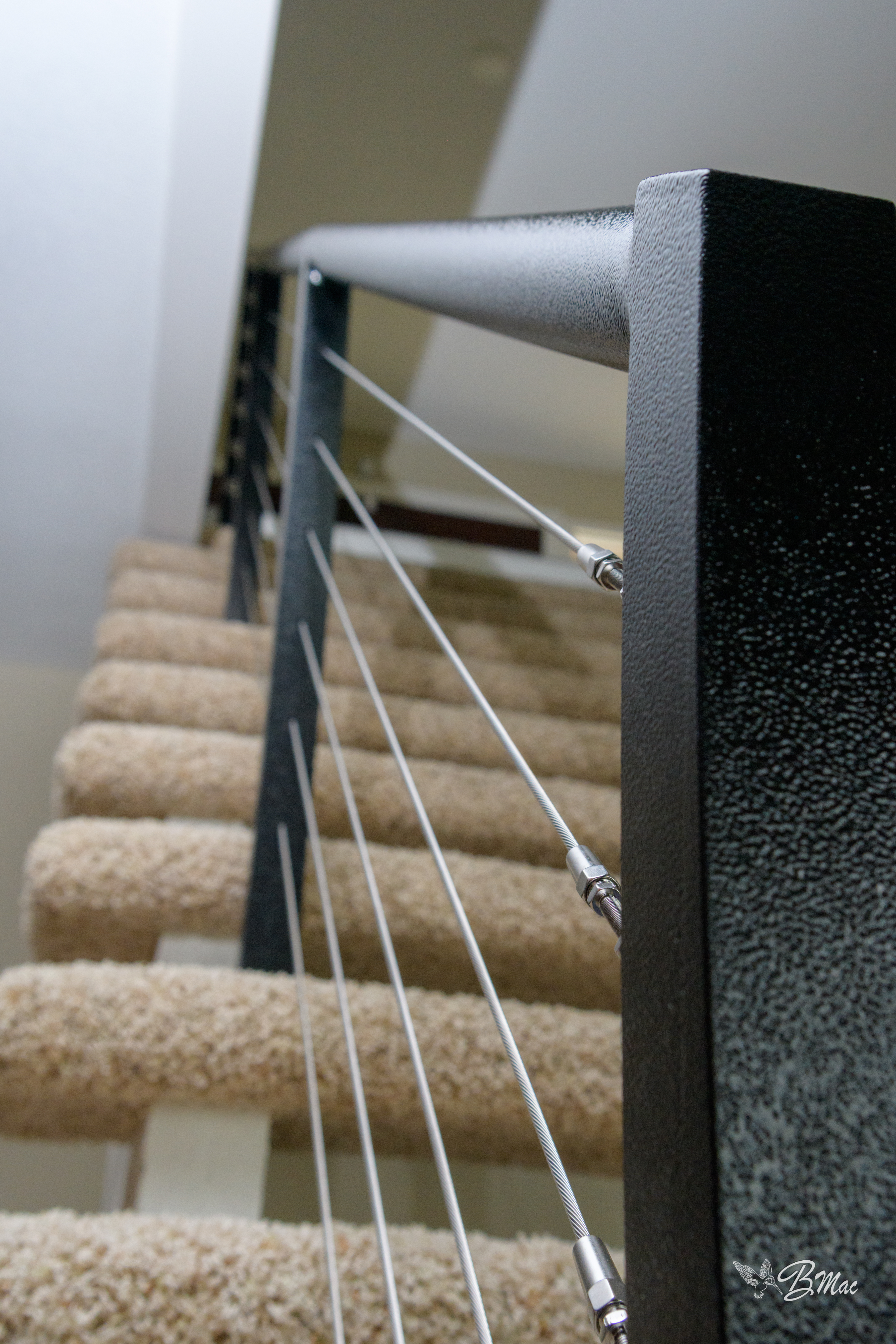 Custom cable-rail staircase detail with stainless cable and black powder-coat posts by Cloke Custom Homes