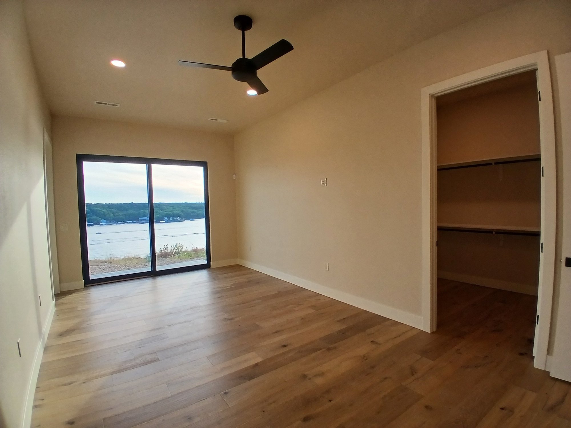 Open great room with wall-to-wall glass and lake views by Cloke Custom Homes