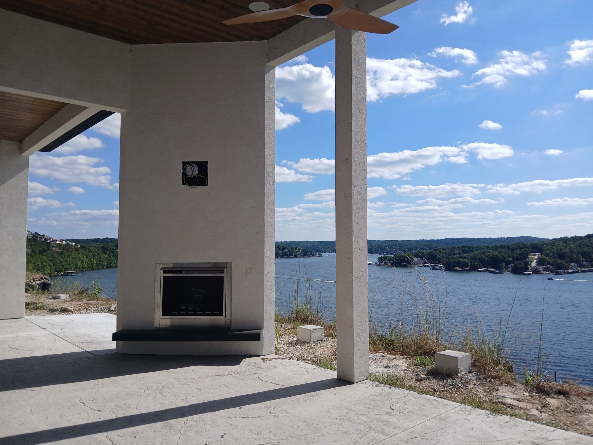 Covered lakeside veranda with stone fireplace overlooking the cove by Cloke Custom Homes