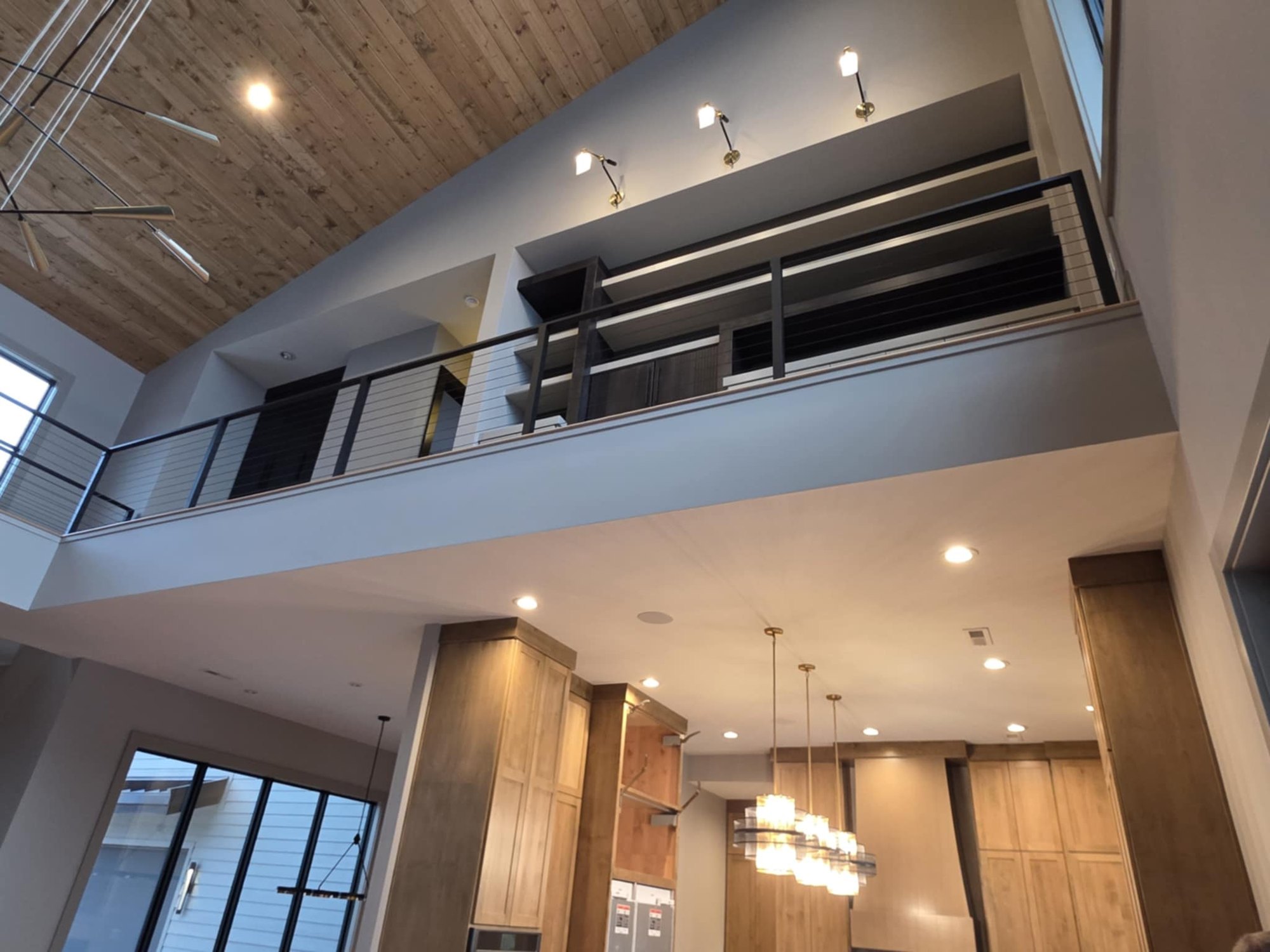 Two-story contemporary great room with wood-clad vaulted ceiling by Cloke Custom Homes