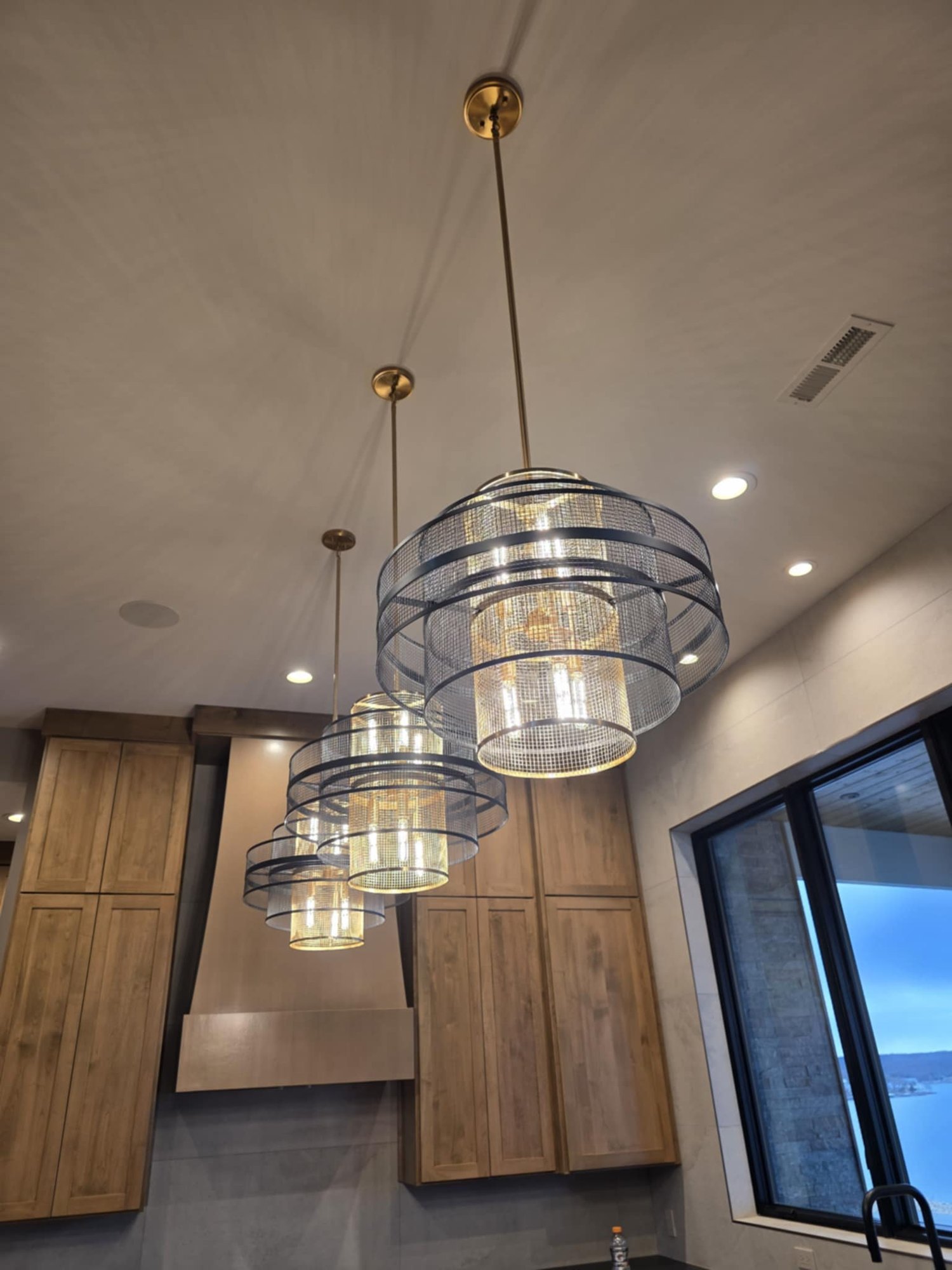 Contemporary dining area with statement lighting and walnut cabinetry by Cloke Custom Homes